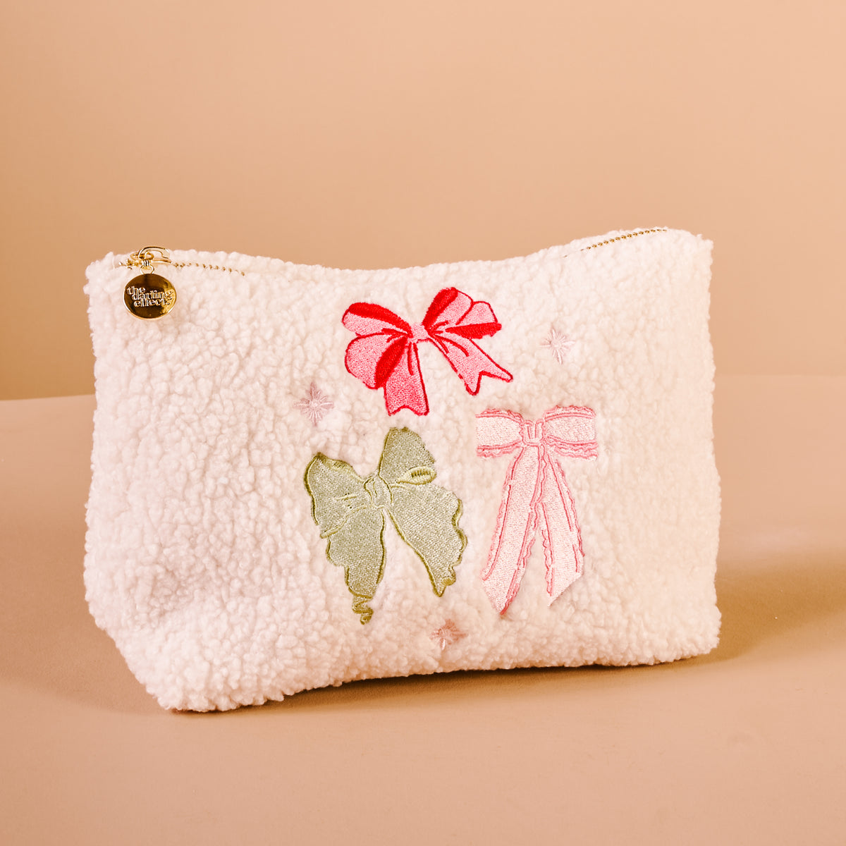 White fluffy pouch with decorative bows on a beige background