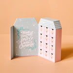 Advent calendar shaped like a house with 'Have Yourself a Merry Little Christmas' text on a beige background