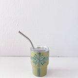 Green cup with a patterned design and metal straw on a white background