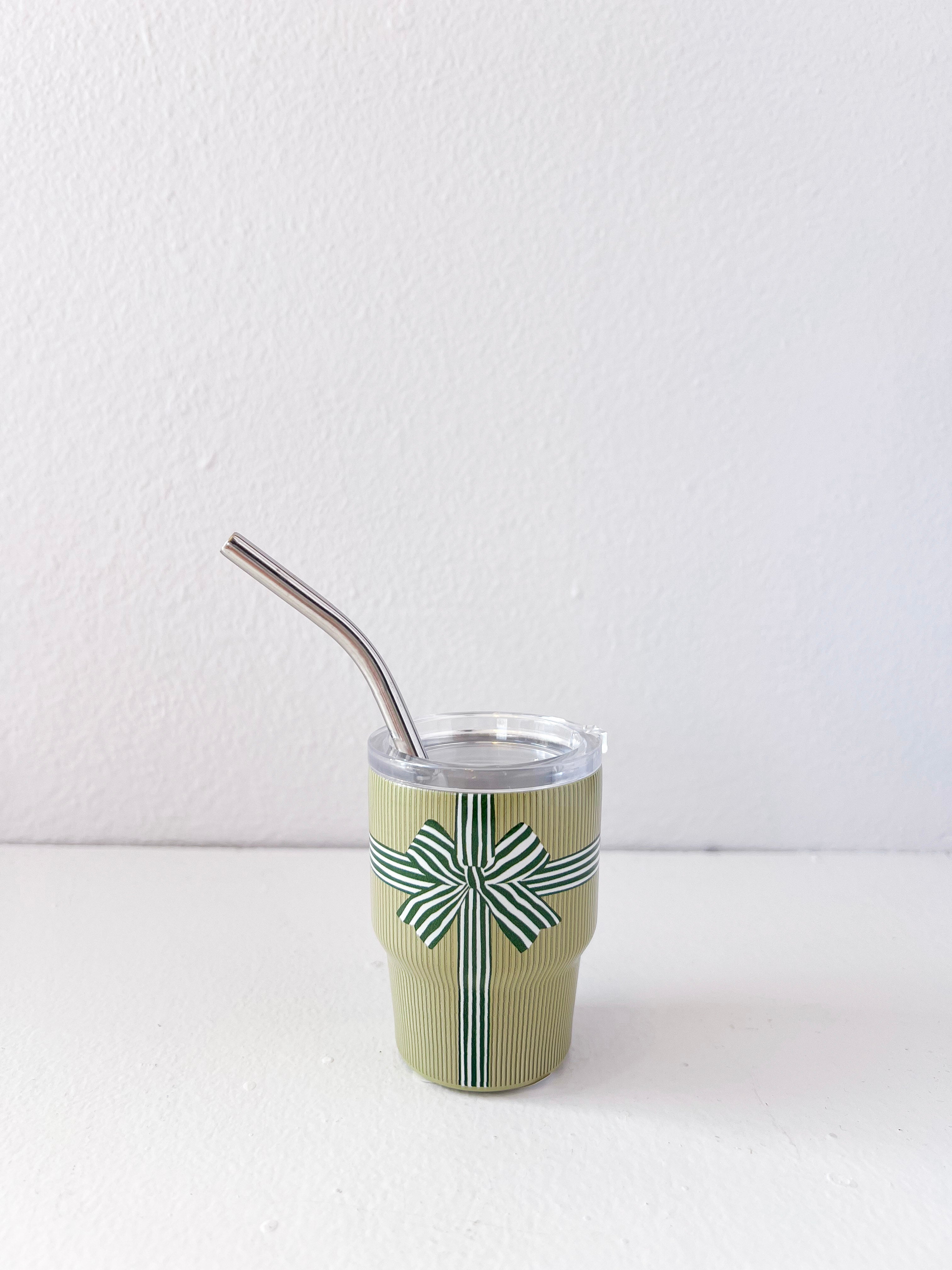 Green cup with a patterned design and metal straw on a white background