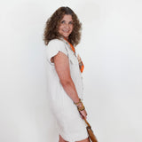 Woman in a white dress holding a paddle against a plain background