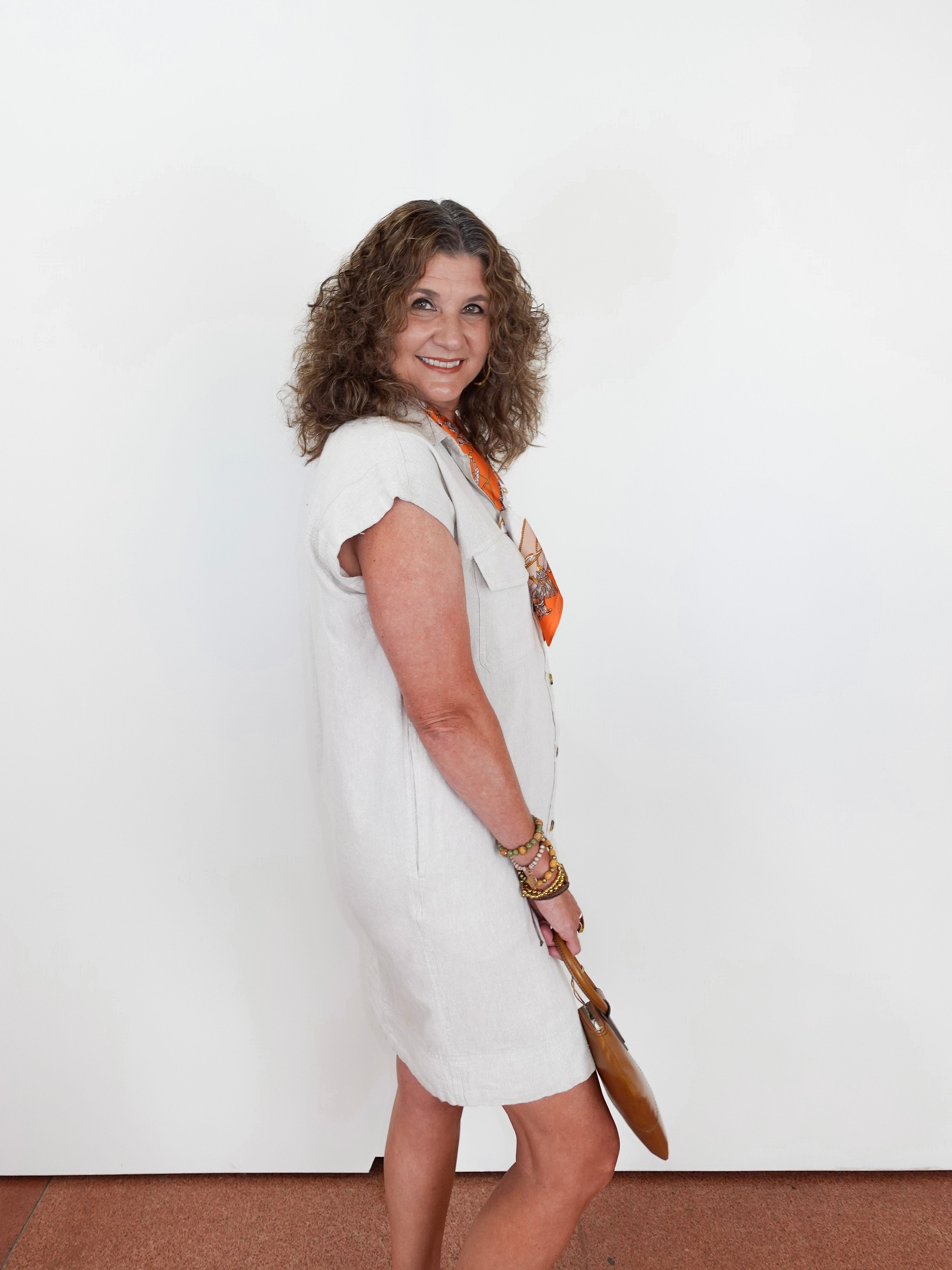 Woman in a white dress holding a paddle against a plain background