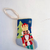 Decorative needlepoint ornament with a nutcracker design on a white background