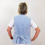 Person wearing a light blue vest over a white shirt on a plain background