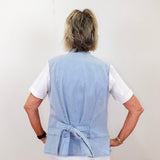 Person wearing a light blue vest over a white shirt on a plain background