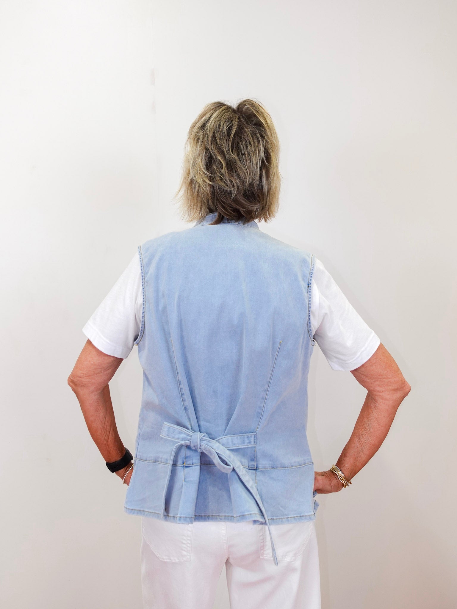 Person wearing a light blue vest over a white shirt on a plain background