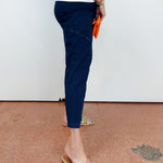 Person wearing navy jogger pants and embellished sandals on a brown floor.