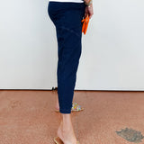 Person wearing navy jogger pants and embellished sandals on a brown floor.