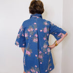 Person wearing a blue floral dress against a white wall