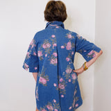 Person wearing a blue floral dress against a white wall