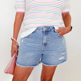 Person wearing a striped shirt and denim shorts with a white background