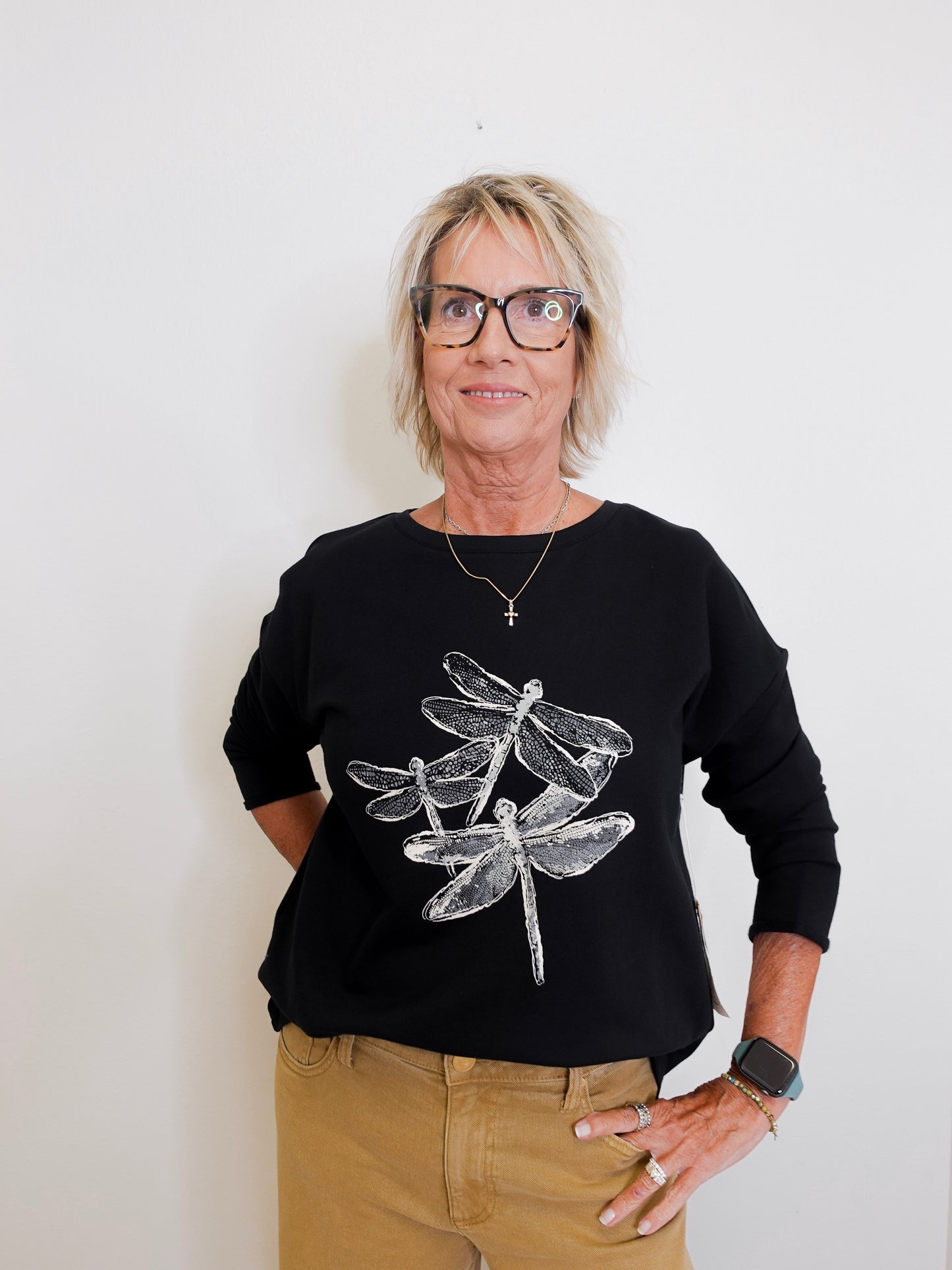Person wearing a black sweater with dragonfly design on a white background