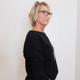 Person wearing a black sweater against a white background