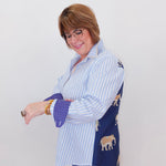 Woman wearing a blue and white striped shirt with a navy cardigan over a white background