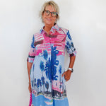 Woman wearing a colorful dress with palm tree design against a white background
