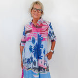 Woman wearing a colorful dress with palm tree design against a white background