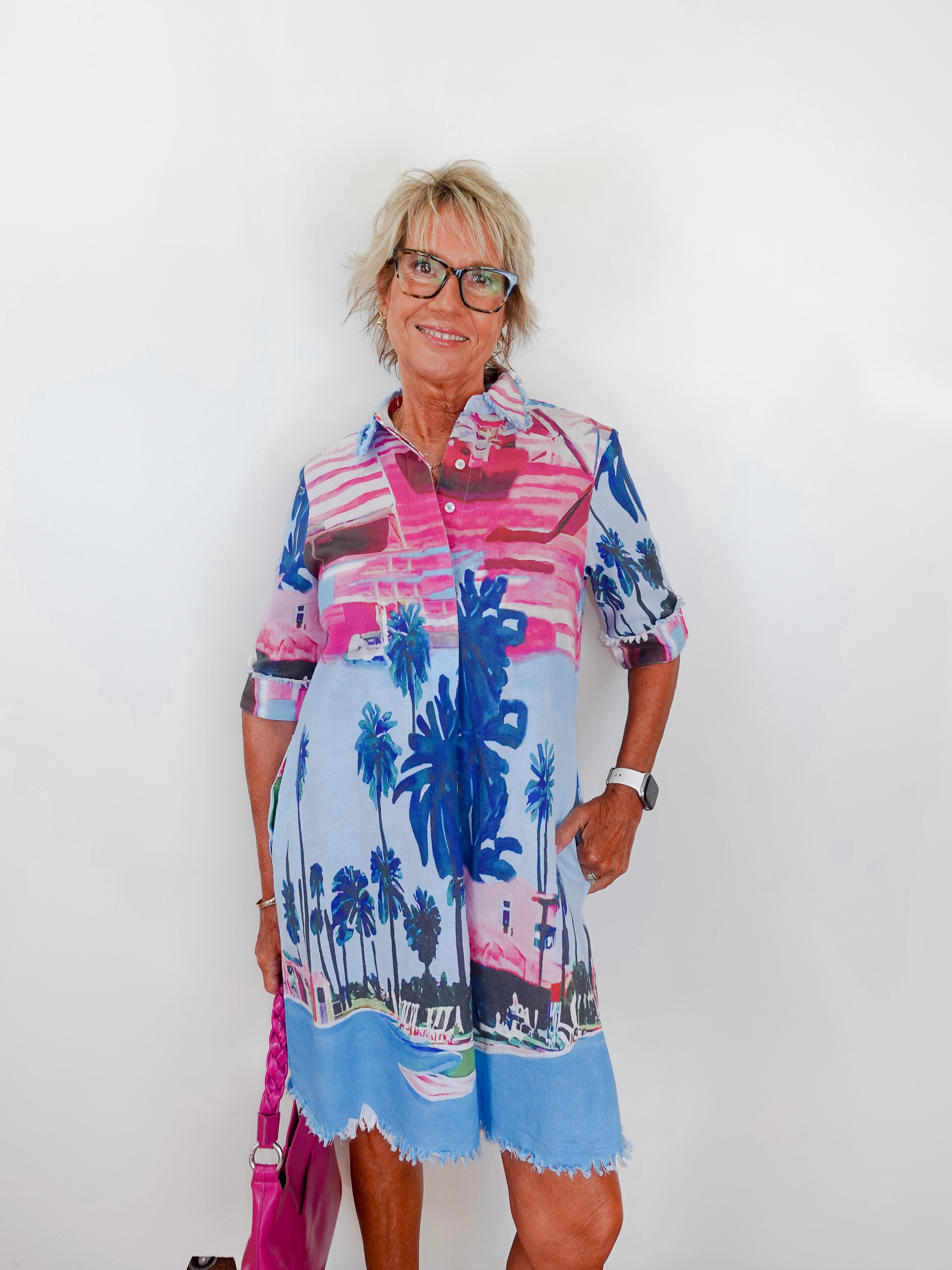 Woman wearing a colorful dress with palm tree design against a white background