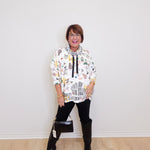 Person wearing a patterned hoodie and black boots on a plain background