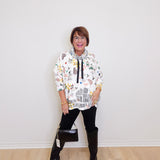 Person wearing a patterned hoodie and black boots on a plain background