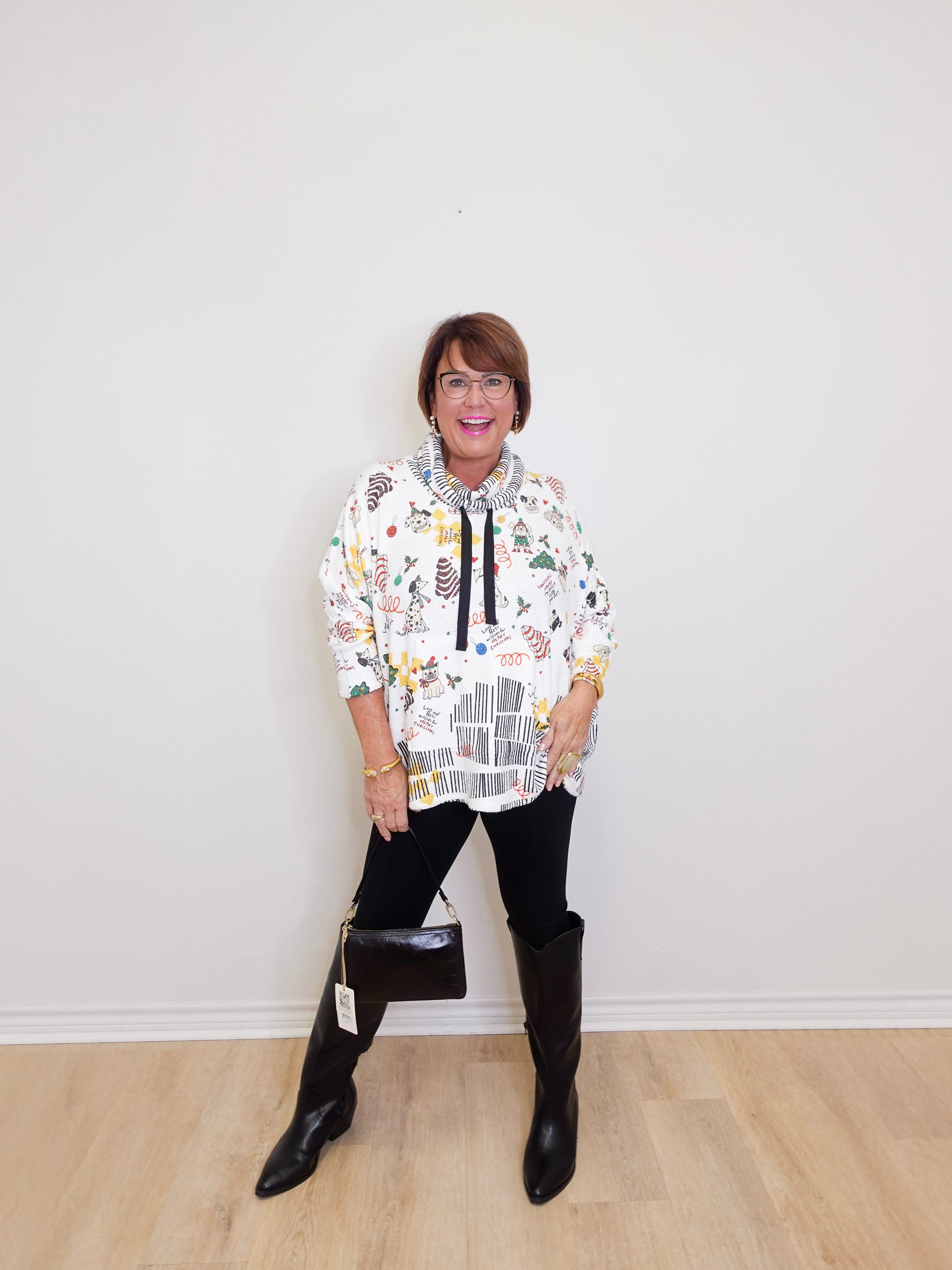 Person wearing a patterned hoodie and black boots on a plain background