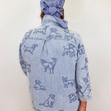 Person wearing a denim jacket with dog patterns and a matching headscarf against a white background