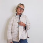 Person wearing a quilted jacket and glasses against a white background