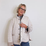 Person wearing a quilted jacket and glasses against a white background