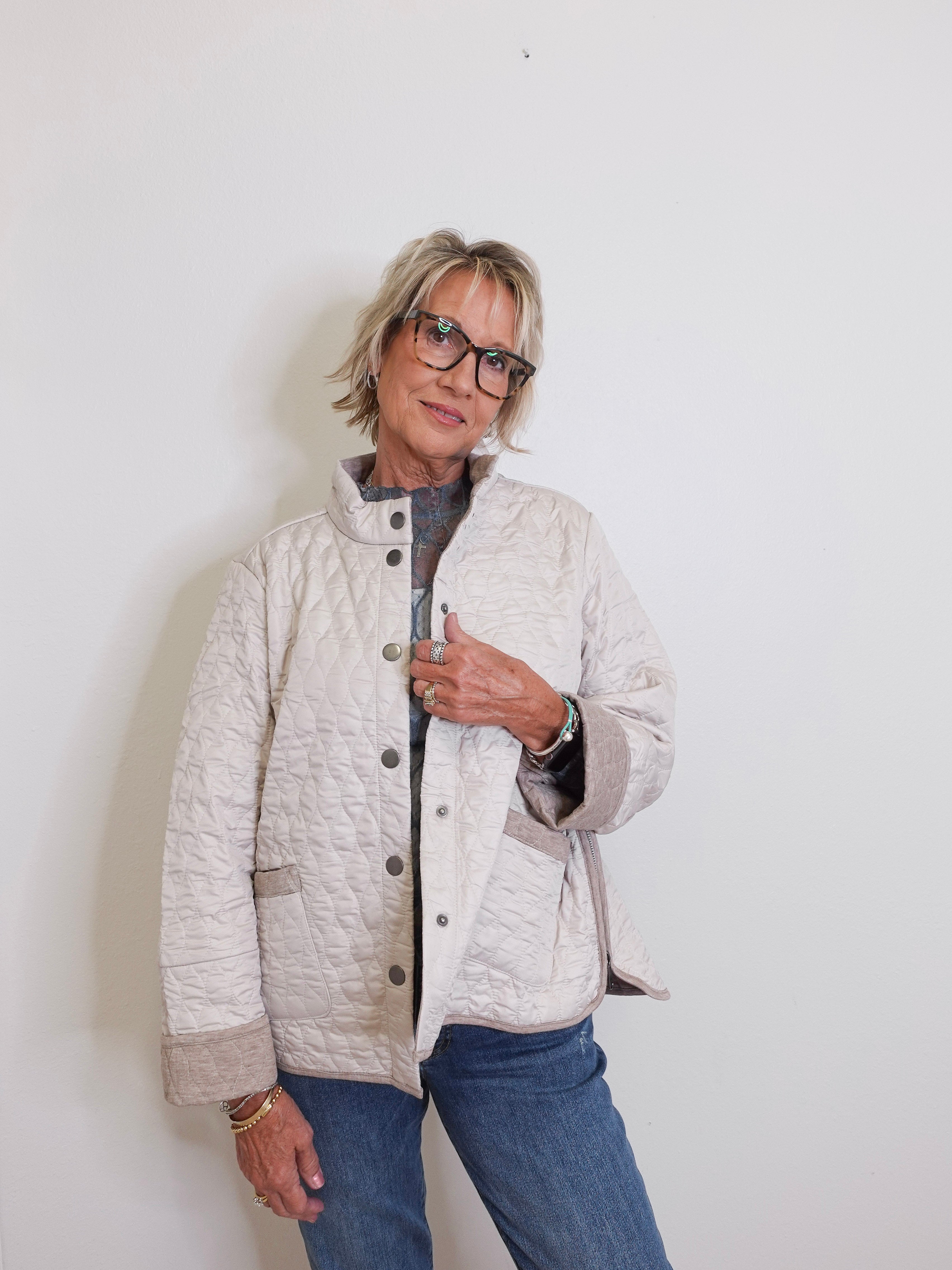 Person wearing a quilted jacket and glasses against a white background