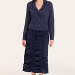 Woman wearing a navy blue outfit with a jacket and skirt on a white background