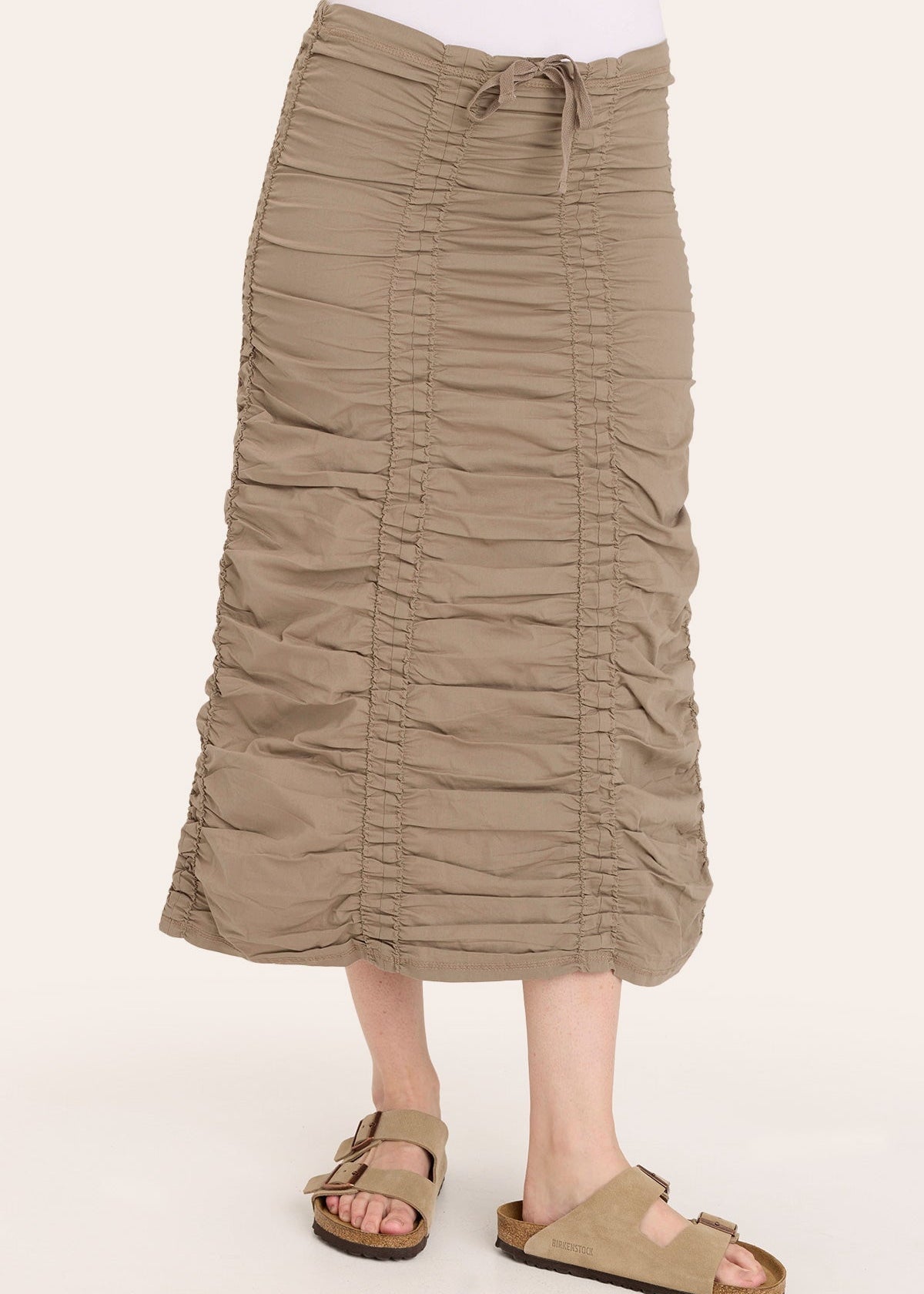 Person wearing a beige ruched skirt on a white background