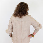 Person wearing a beige blouse with long sleeves on a white background