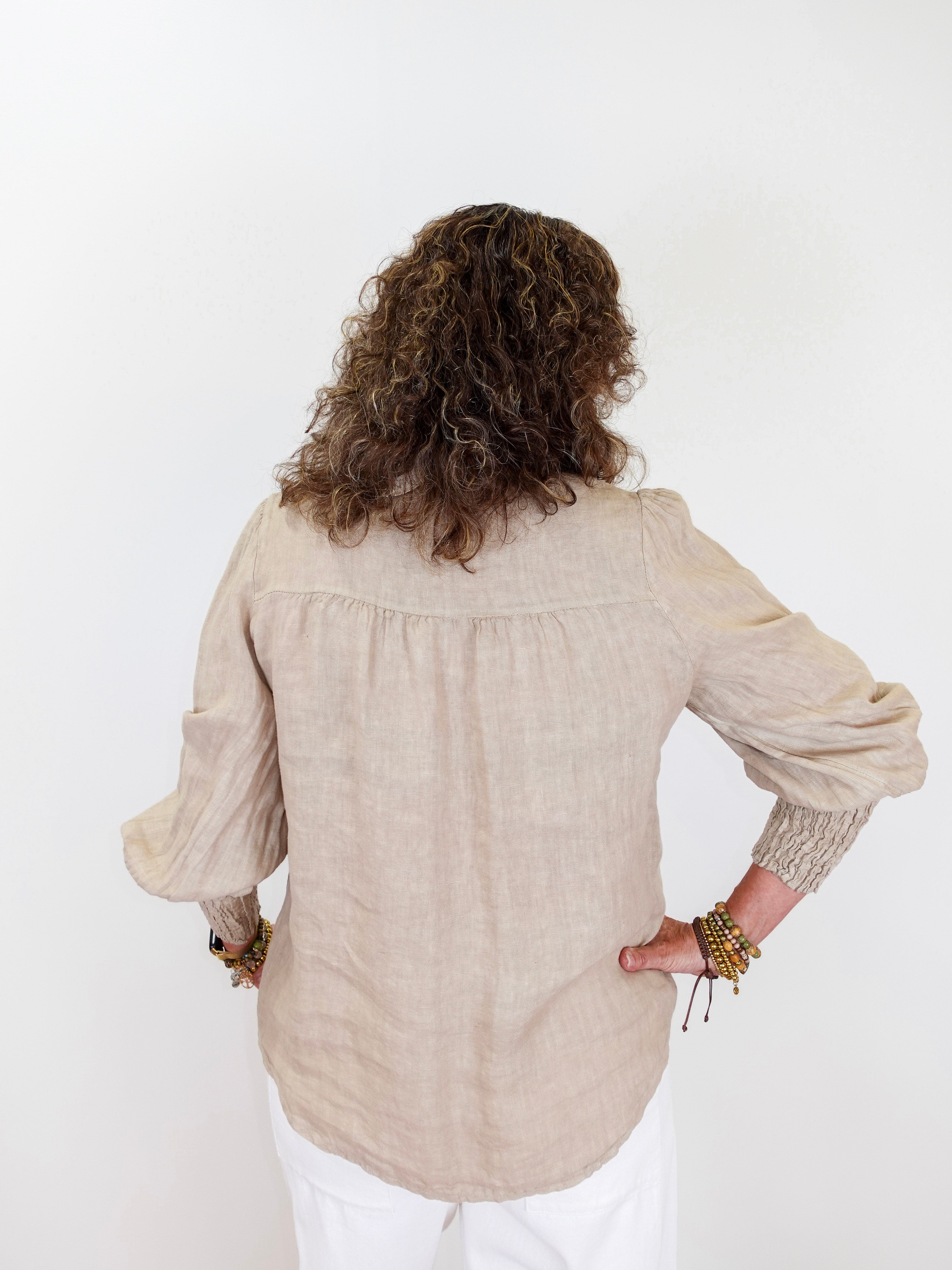 Person wearing a beige blouse with long sleeves on a white background