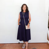 Woman wearing a navy dress with a white wall background