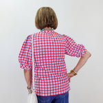 Person wearing a red and white checkered shirt against a plain background