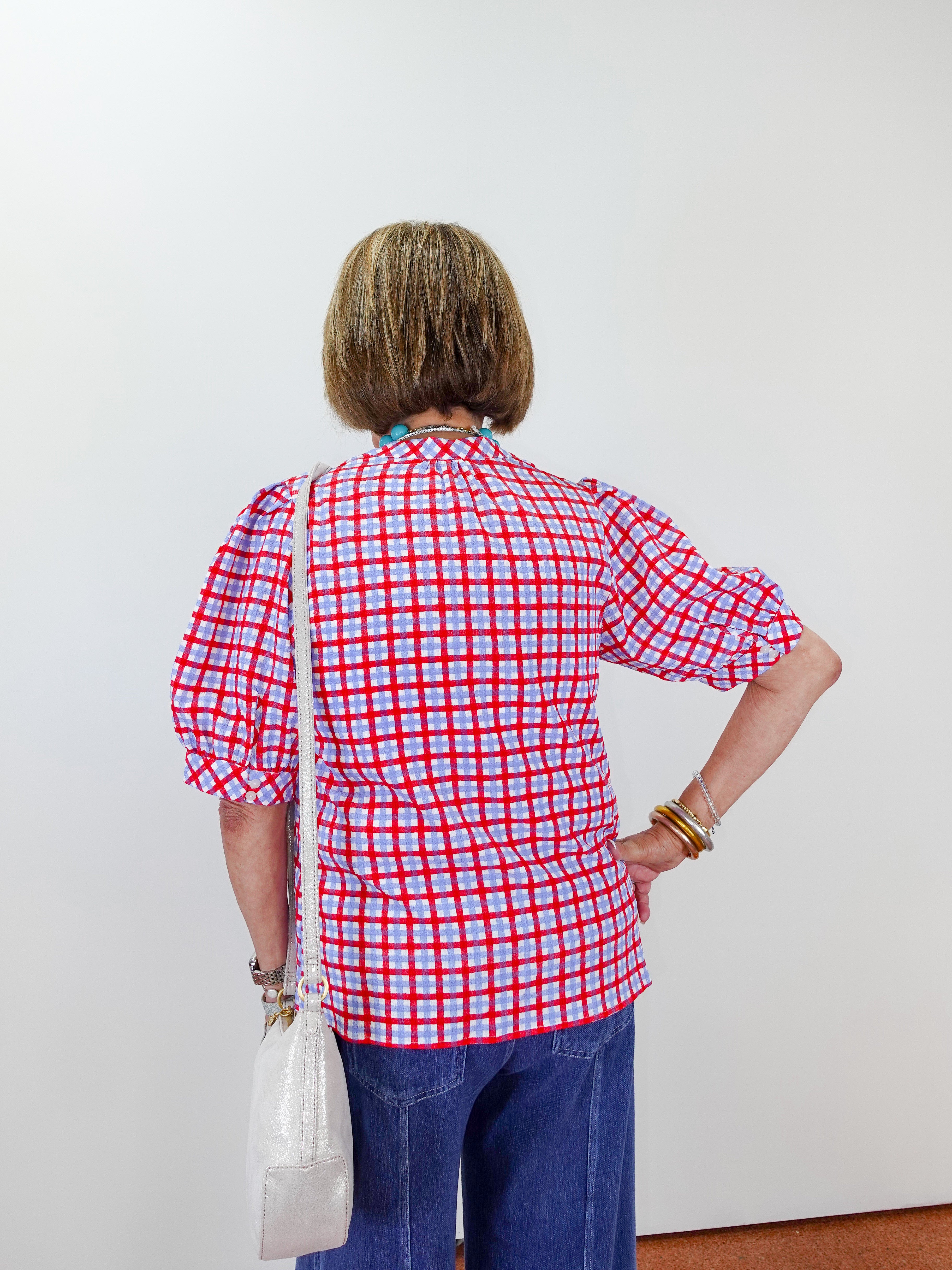 Person wearing a red and white checkered shirt against a plain background