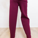 Maroon tracksuit worn by a person on a light wooden floor.