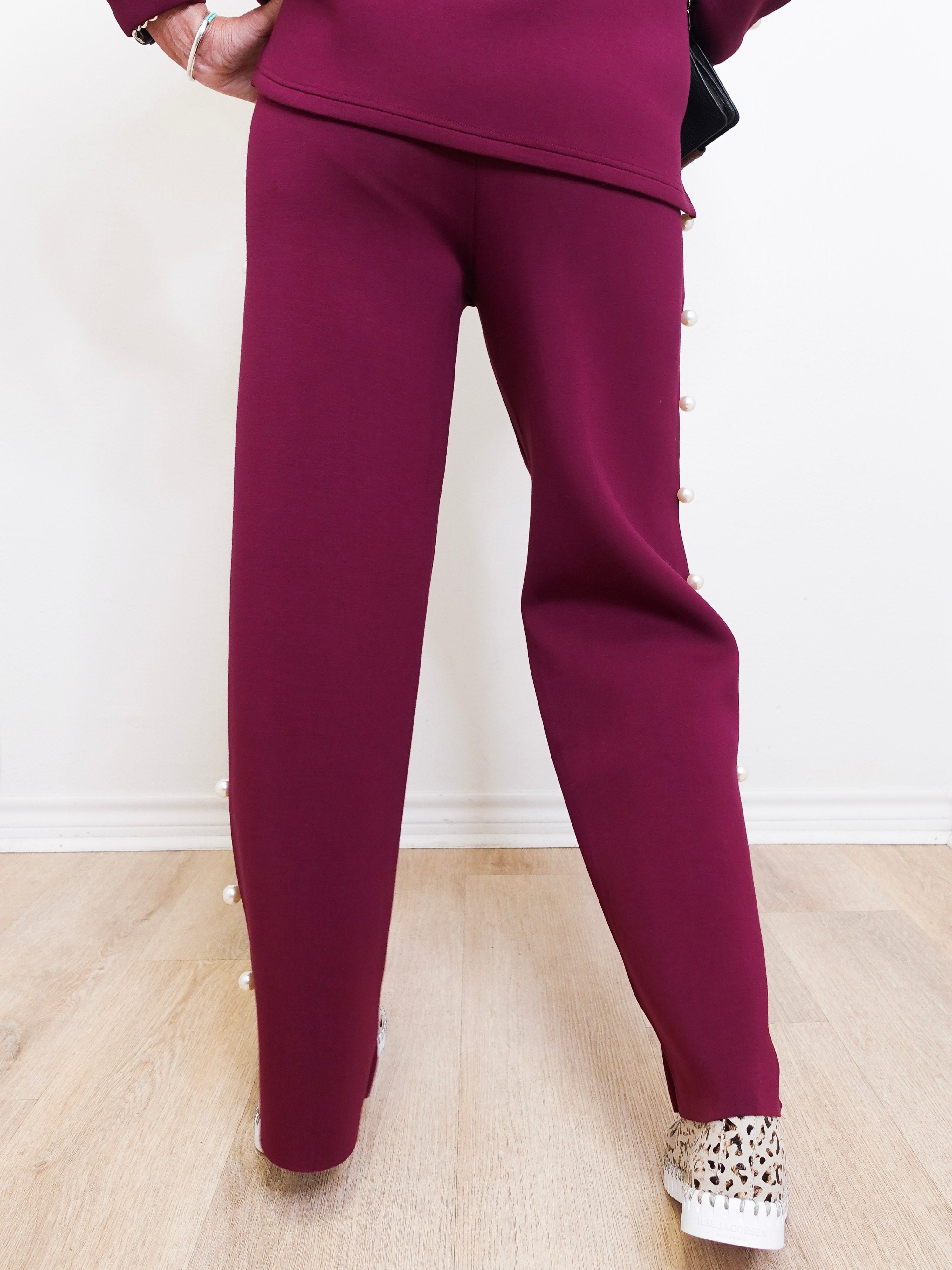 Maroon tracksuit worn by a person on a light wooden floor.