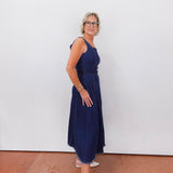 Woman wearing a blue dress standing against a white wall.