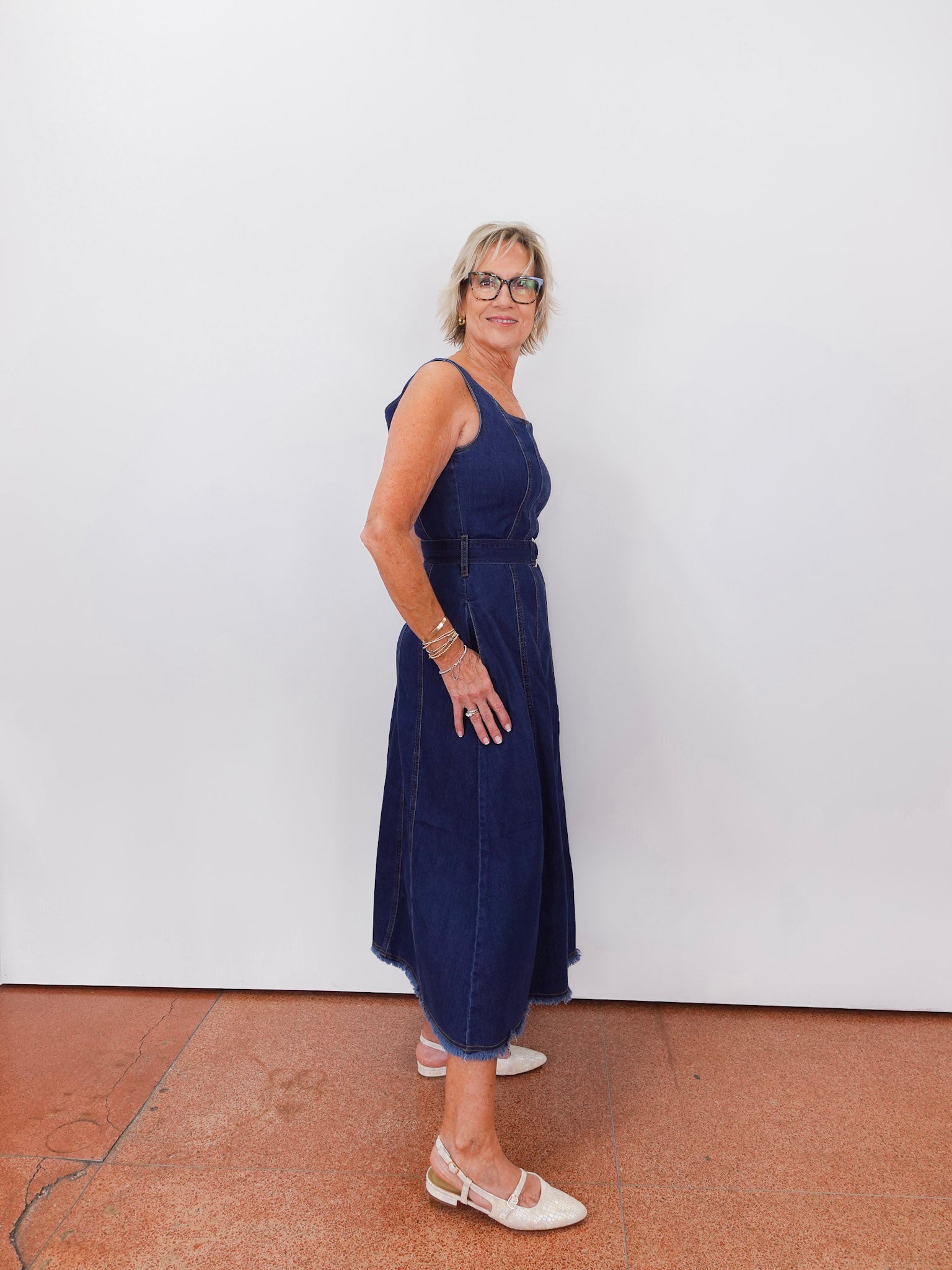 Woman wearing a blue dress standing against a white wall.