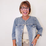 Woman wearing a denim jacket with a plain background