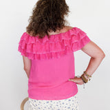 Person wearing a pink ruffled top and floral pants against a white background