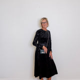 Woman wearing a black dress with a white wall background