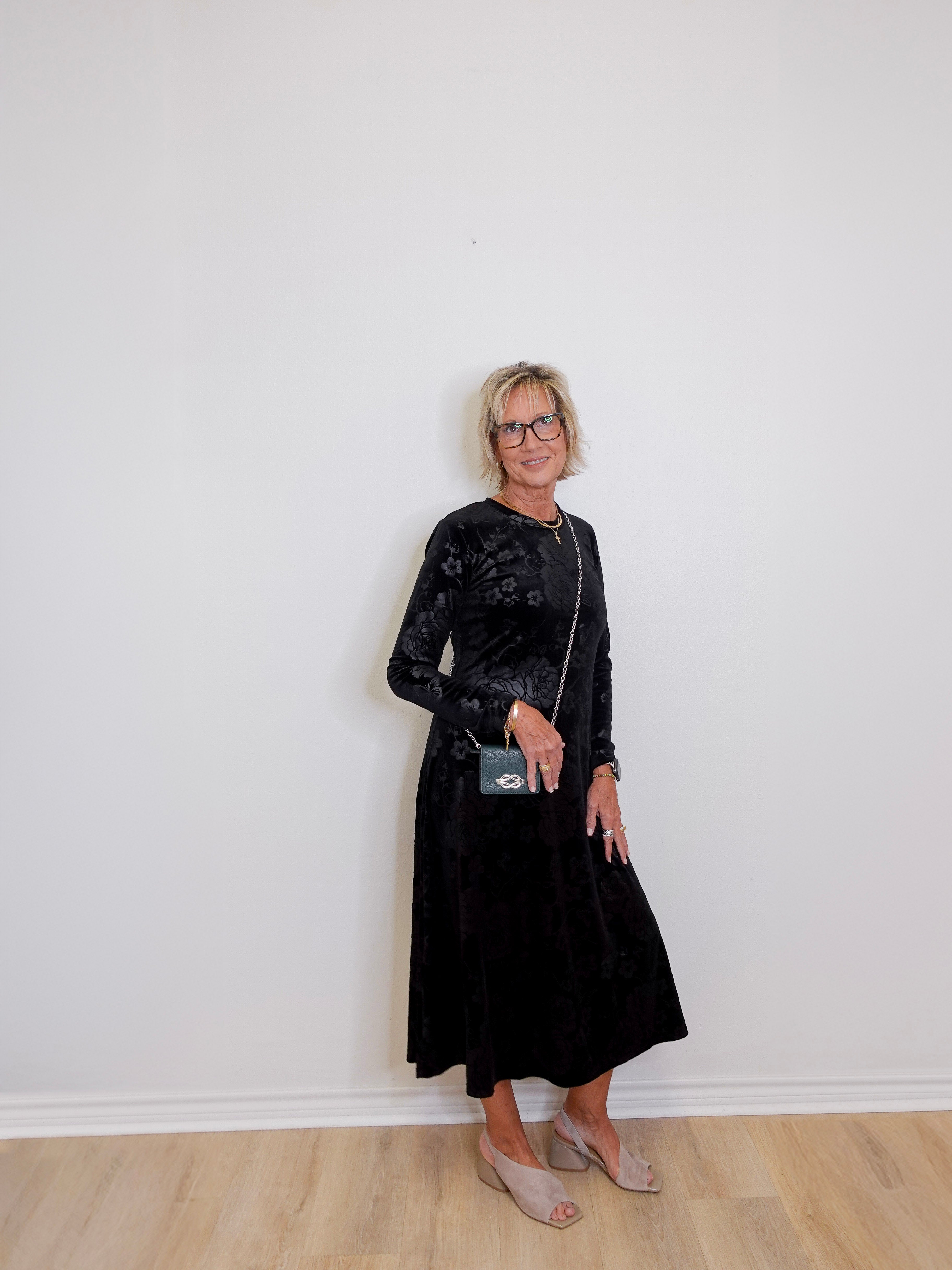 Woman wearing a black dress with a white wall background