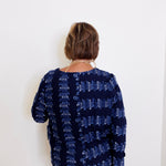 Person wearing a navy blue patterned top against a white background