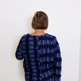 Person wearing a navy blue patterned top against a white background