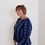 Woman wearing a navy patterned blouse against a white wall