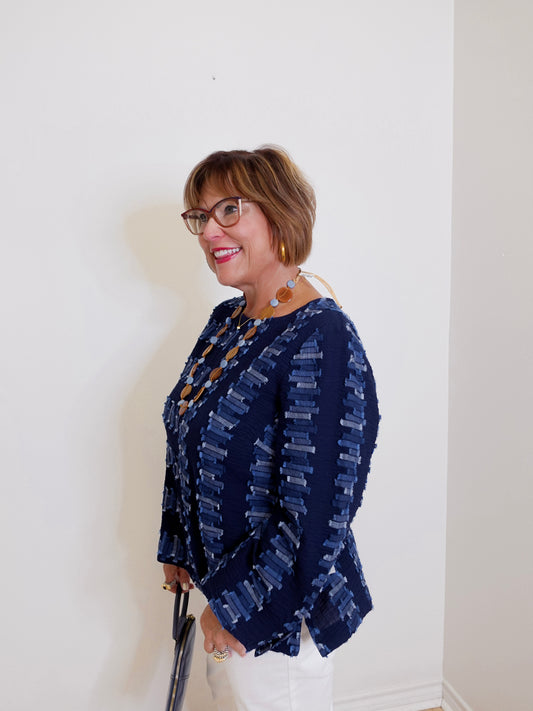 Woman wearing a navy patterned blouse against a white wall