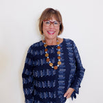 Woman wearing a navy patterned top with a white background