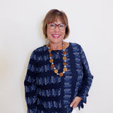 Woman wearing a navy patterned top with a white background