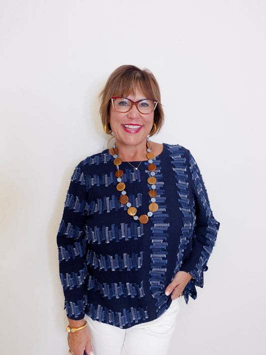Woman wearing a navy patterned top with a white background